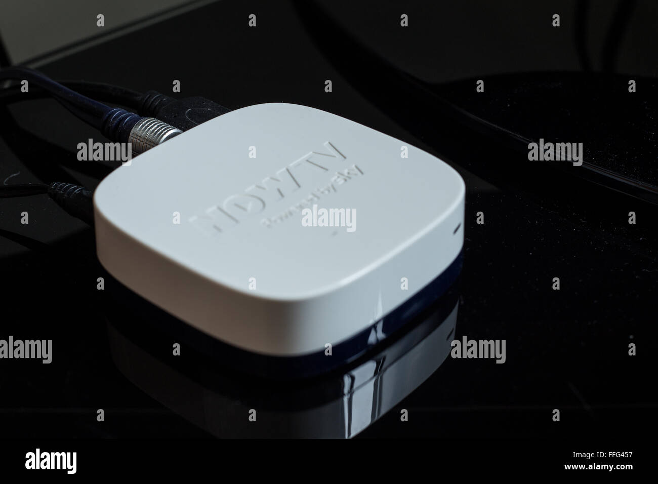 A white Sky Now TV top box plugged in on top of a television stand with  'Now TV' logo showing Stock Photo - Alamy