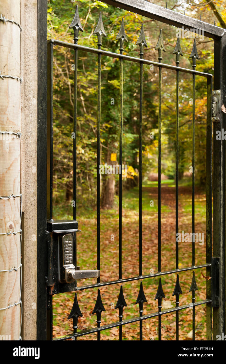 A lock with a keypad and security code on an outside gate leading to a country path. Stock Photo