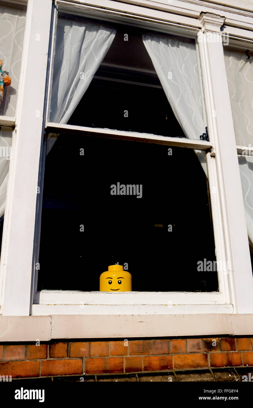 A Lego storage head at the window of a house. Stock Photo