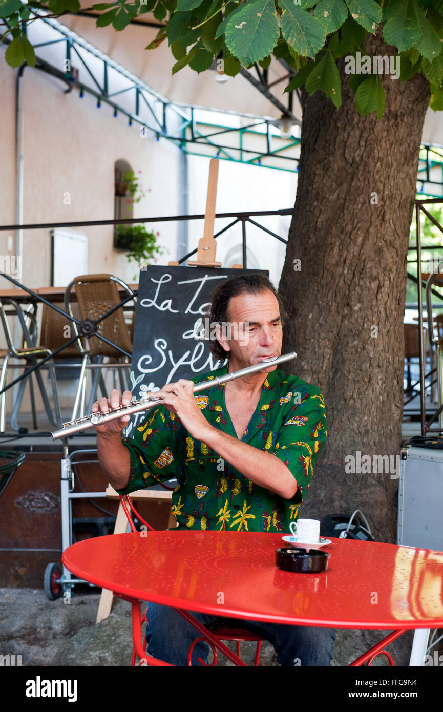 Flute player at red table under a tree  in Provence France Europe Stock Photo