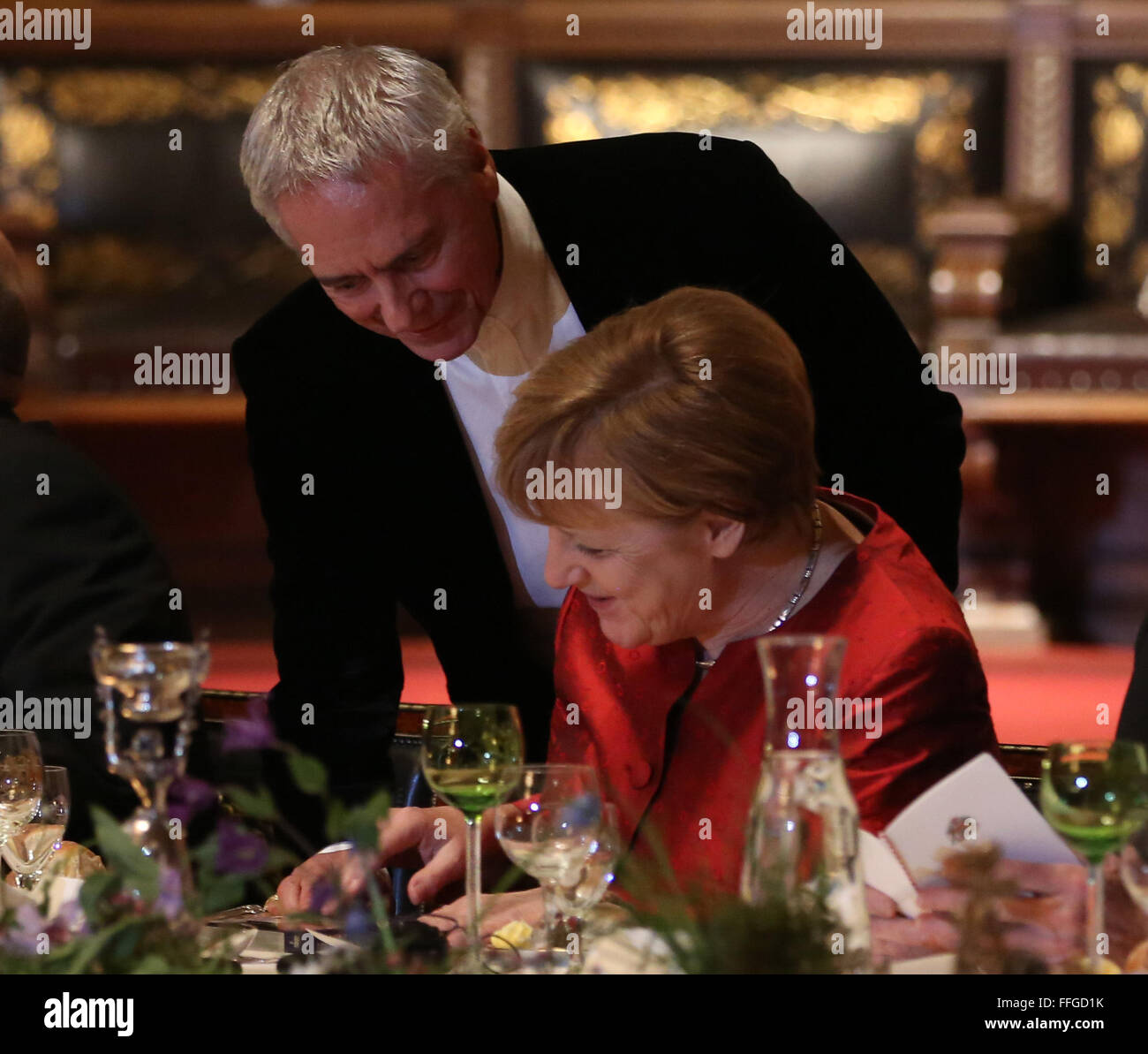 Hamburg, Germany. 12th Feb, 2016. German Chancellor Angela Merkel (R) is handed a DVD by John Neumeier, ballet director and chief choreographer at the Hamburg State Opera, at the annual Matthiae dinner at the city hall of Hamburg, Germany, 12 February 2016. Britain's Prime Minister David Cameron and German Chancellor Angela Merkel are guests of honour at the oldest feast in the world. Since 1356, the leaders of the Hansa city invite distinguished guests to the Matthiae dinner. Photo: CHRISTIAN CHARISIUS/dpa/Alamy Live News Stock Photo