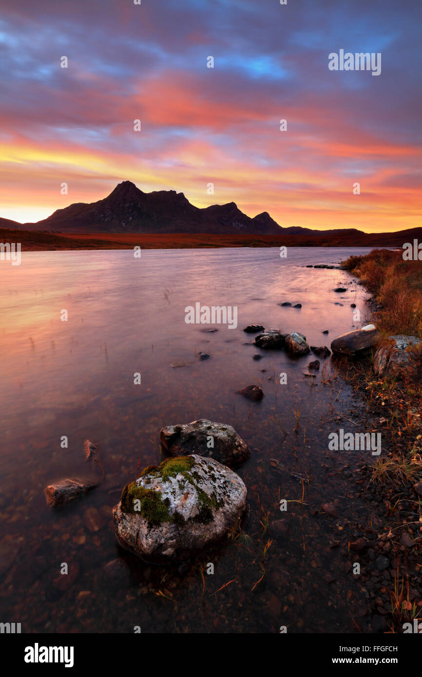 Rocks on the shore of Loch Hakel captured at sunrise in early November,  with Ben Loyal in the distance. Stock Photo