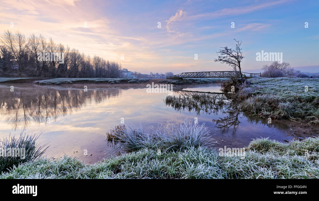 Cold frosty morning looking across the river stour with footbridge on Sudbury meadows, Suffolk, England. Stock Photo