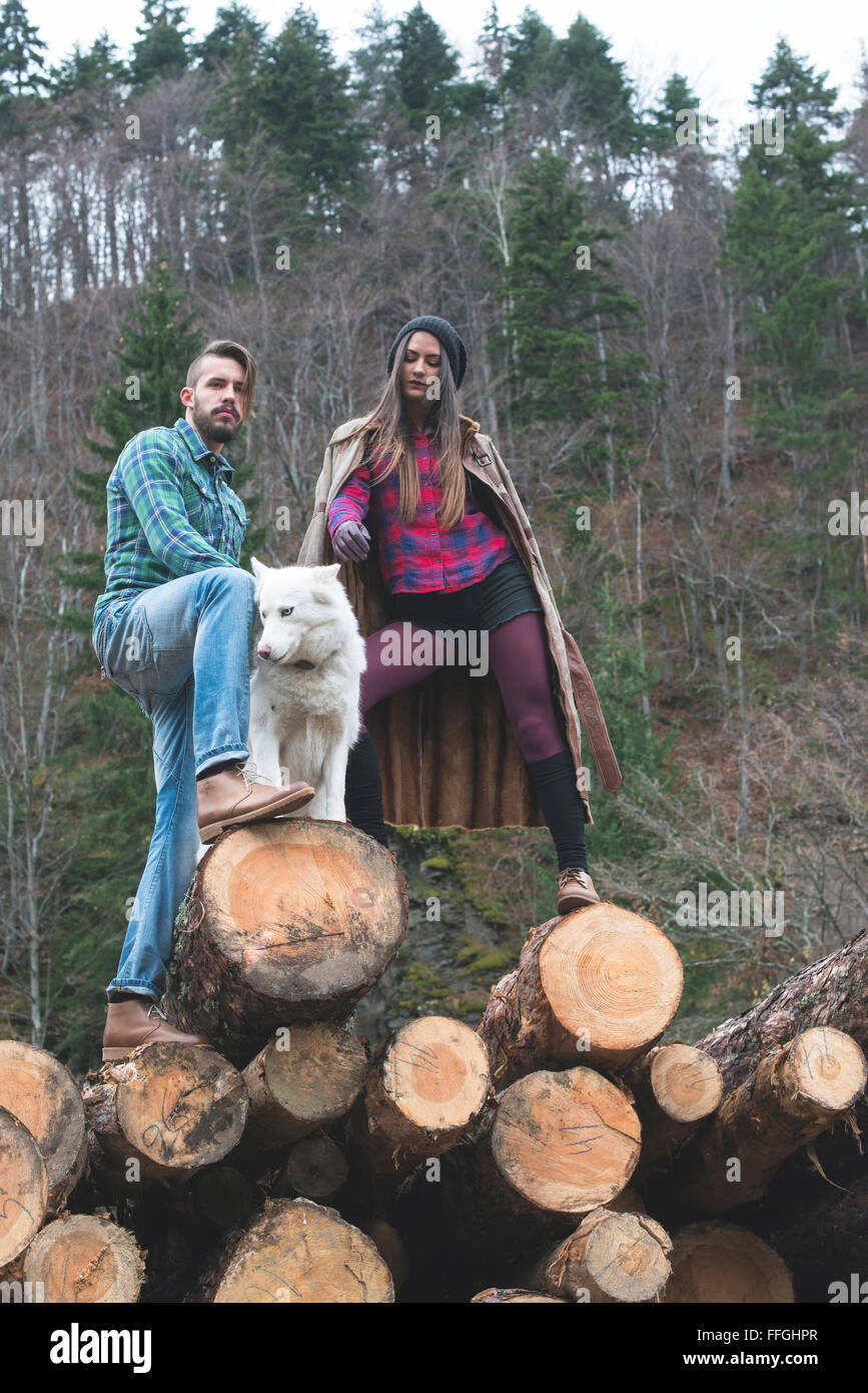 Young woman and men on wood logs in the forest. White dog Stock Photo ...