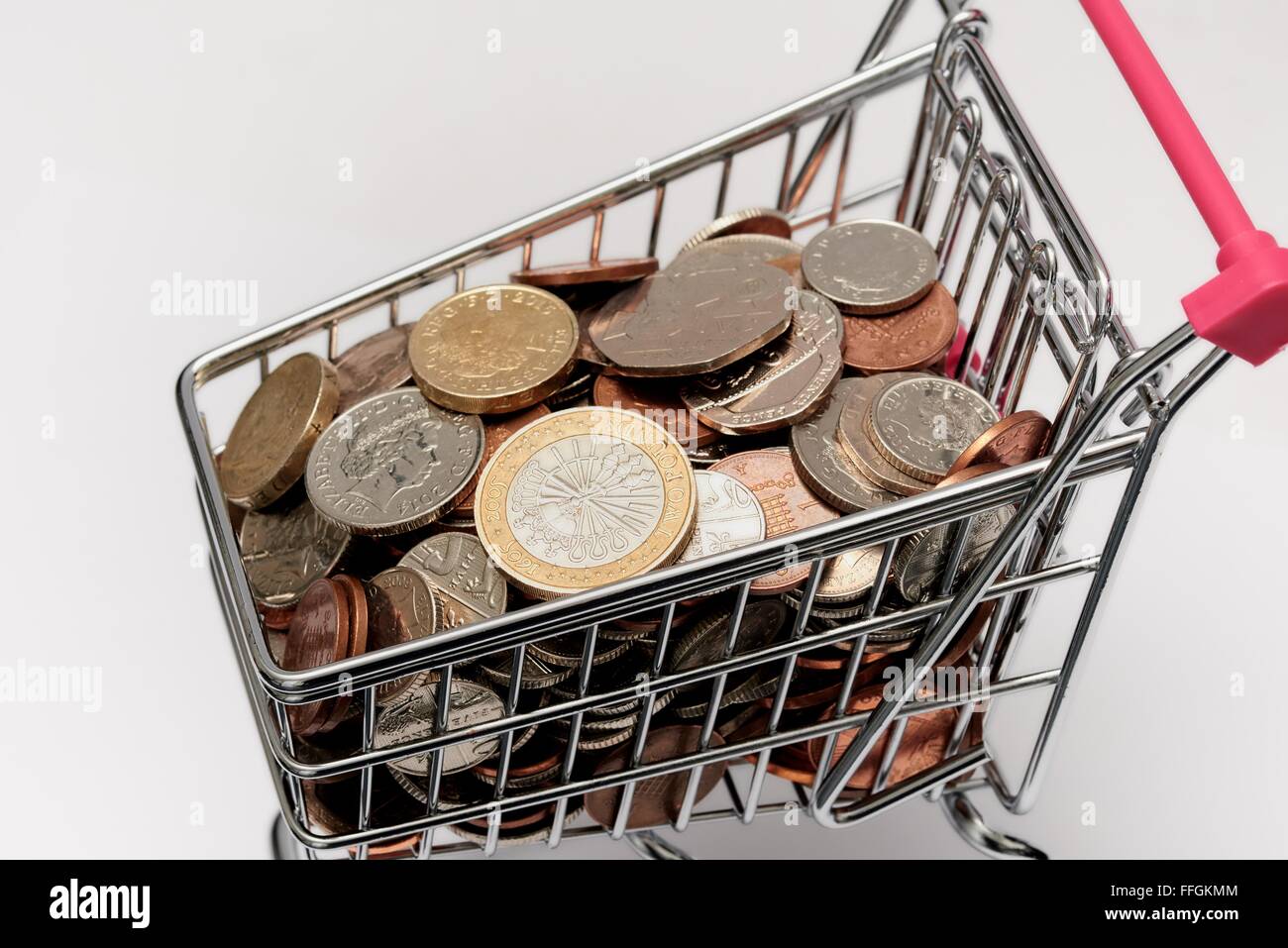 Small supermarket shopping trolley with coins inside. Cost of living