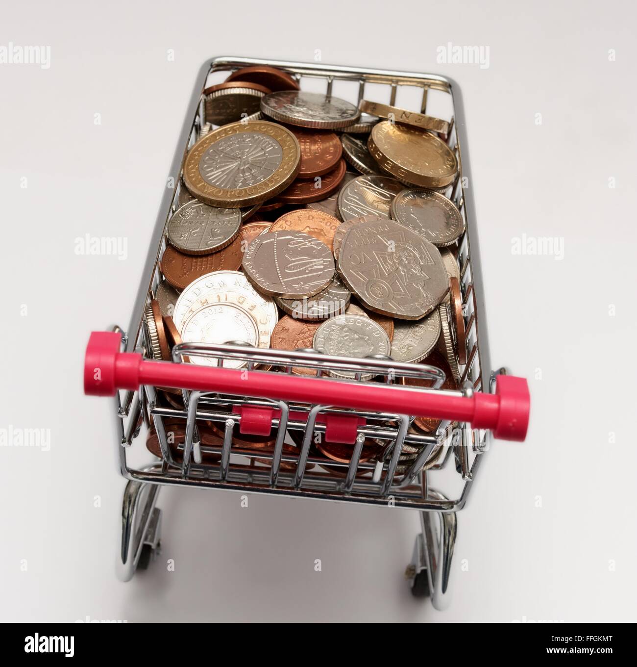 Small supermarket shopping trolley with coins inside. Cost of living