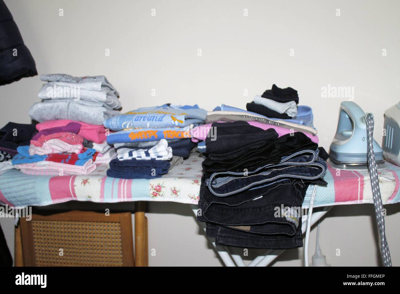 ironing board with folded clothes and iron Stock Photo