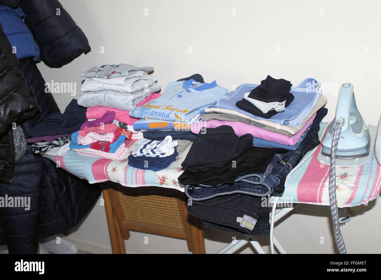 ironing board with folded clothes and iron Stock Photo