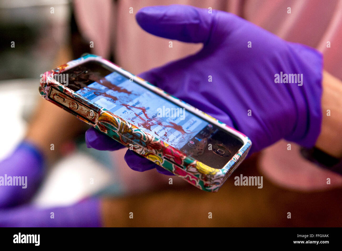 A CSTARS student holds the bloody cell phone of a young female driver admitted in the the shock trauma center after she was involved in a motor vehicle collision. Stock Photo