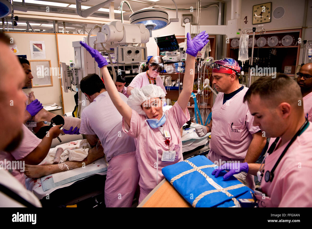 A TRU physician makes her way around the bed of an incoming patient while CSTARS students and TRU technicians rush to apply care. During an emergency transfer 10 to 20 technicians and physicians make their way in and out of the individual trauma station to provide to the patient. Stock Photo