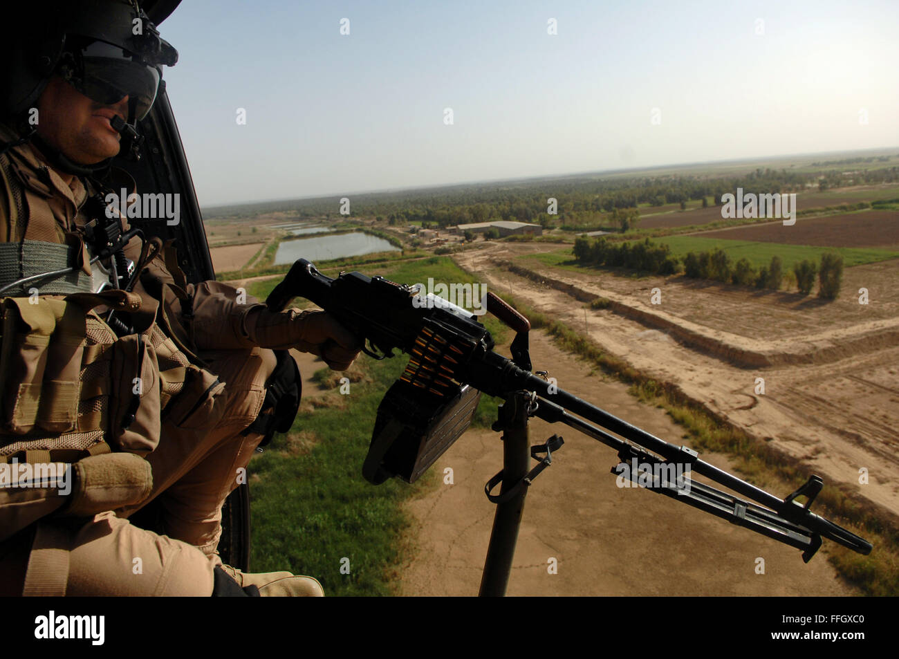 Tech. Sgt. Anthony Taber, Multinational Security Transition Command-Iraq aerial gunner, performs air-to-ground reconnaissance on the way to Balad Air Base in a UH-1. Stock Photo