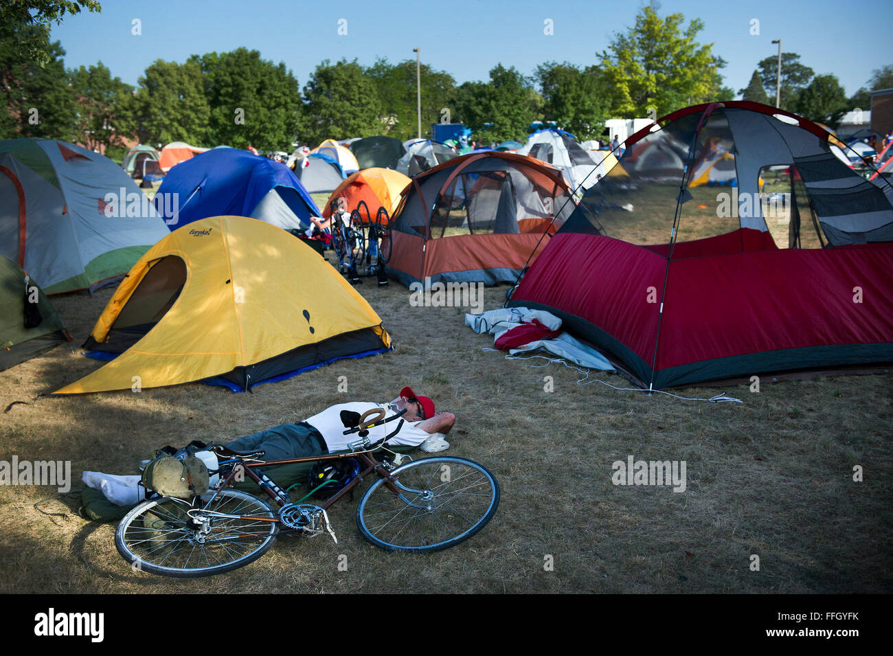 A RAGBRAI participant rests next to his bicycle in one of many open fields converted to a camp site in Webster City, Iowa. Any available park, yard or lot was used for camping grounds to accommodate the more than 20,000 riders. Stock Photo