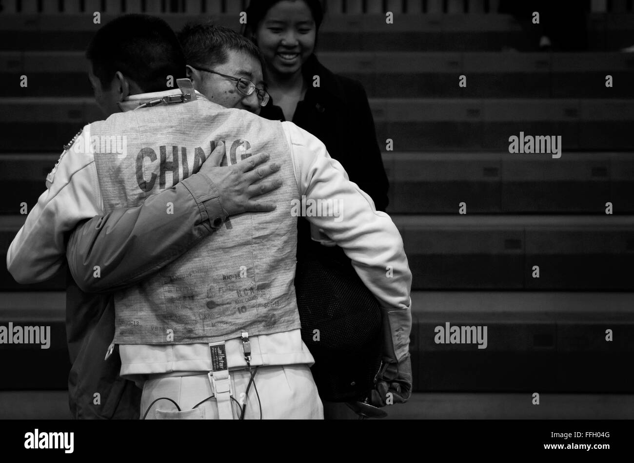 After seeing his family arrive to watch him compete, Alexander Chiang gives his father a hug during warmups of the 2014 NCAA Fencing Championships at Ohio State University. Chiang's family drove from Georgia to Ohio to watch him fence. Stock Photo