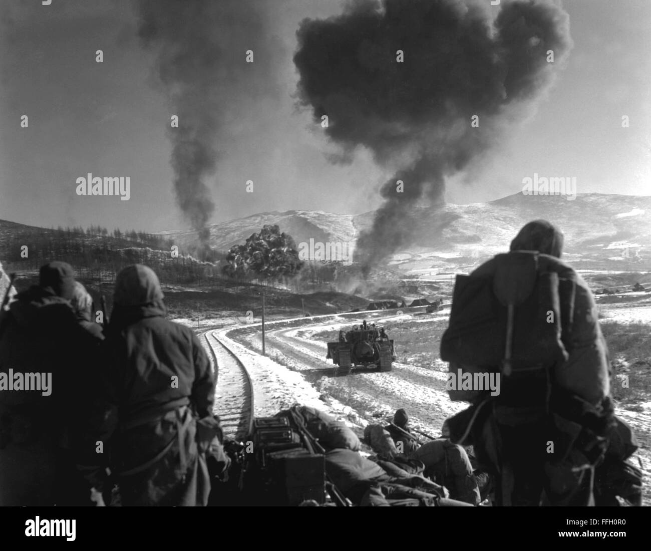 This is one of a series of three remarkable combat photographs showing the close coordination of the United States Marine air and ground units during recent fighting with Chinese Communists in Korea.  United States Marines drive forward after effective close air support of F4U-5 Corsairs.  Billows of smoke and flame from a small target area bear out the accuracy of the flying Leathernecks' Stock Photo
