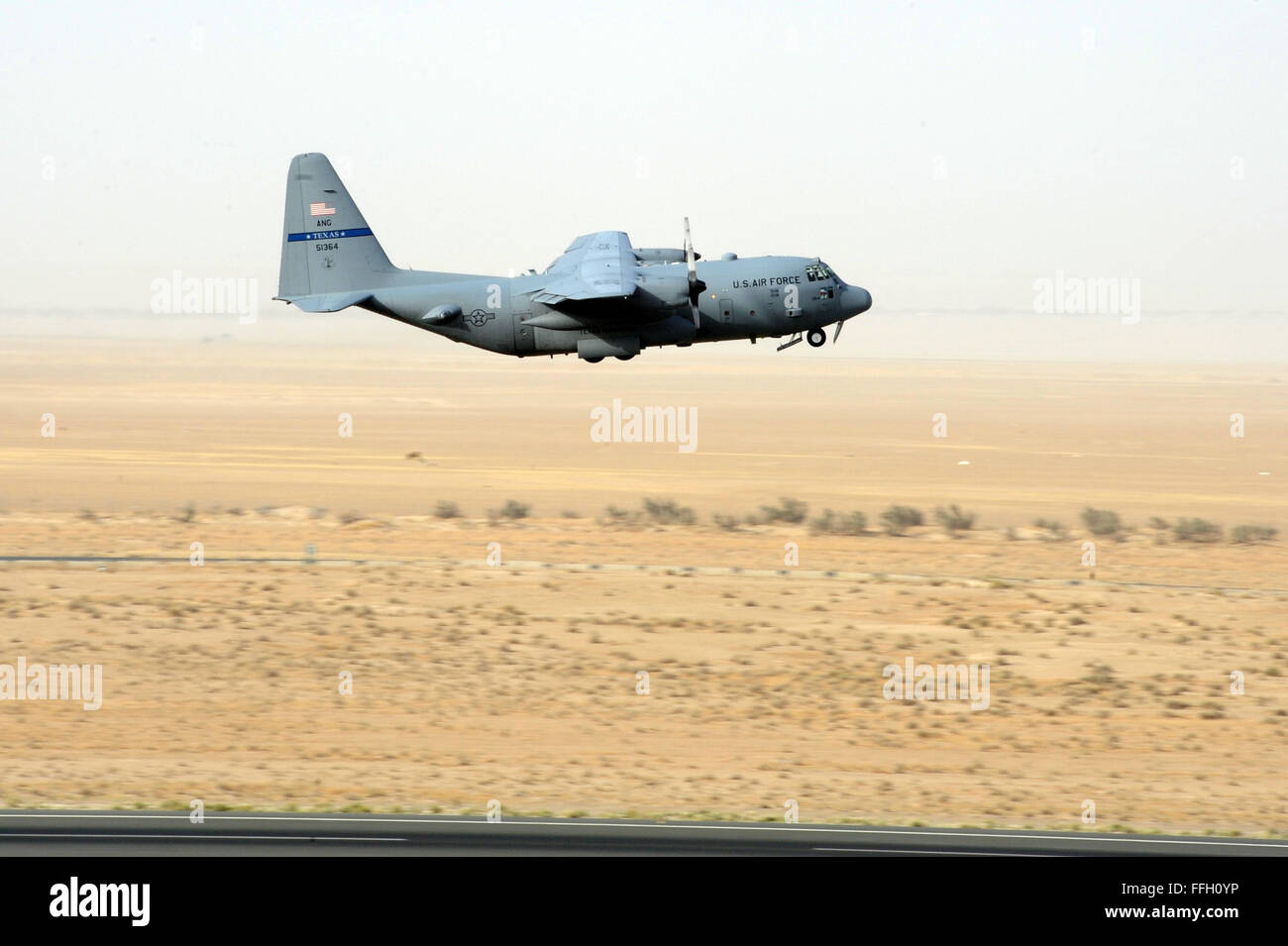 An Air Mobility Command C-130 Hercules deployed from the Texas Air National Guard lifts off from in Southwest Asia. The C-130 primarily performs the tactical portion of the airlift mission. The aircraft is capable of operating from rough, dirt strips and is the prime transport for airdropping troops and equipment into hostile areas. Stock Photo