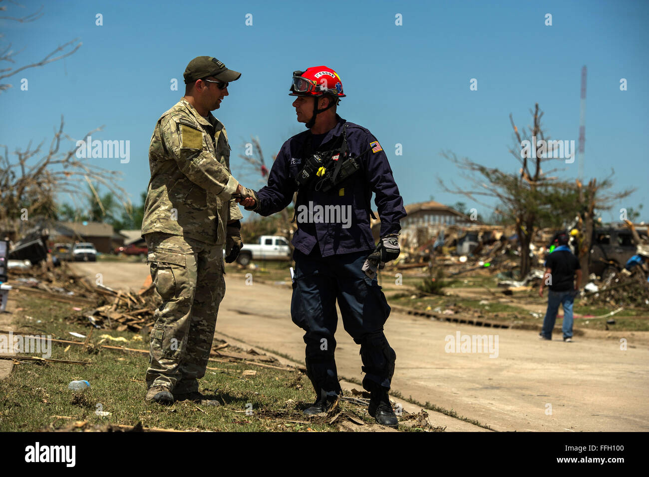 U.S. Air Force Tech. Sgt. Brandon White, Joint Terminal Attack Controller assigned to the 138th Combat Training Flight, talk with local a firefighter May 22, 2013, in Moore, Okla. On Monday a EF-5 tornado, with winds reaching at least 200 mph, traveled for 20 miles, leaving a two-mile-wide path of destruction, leveling homes, crushing vehicles, and killing more than 20 people. More than 115 Oklahoma National Guard have been activated to assist in the rescue and relief efforts. Stock Photo