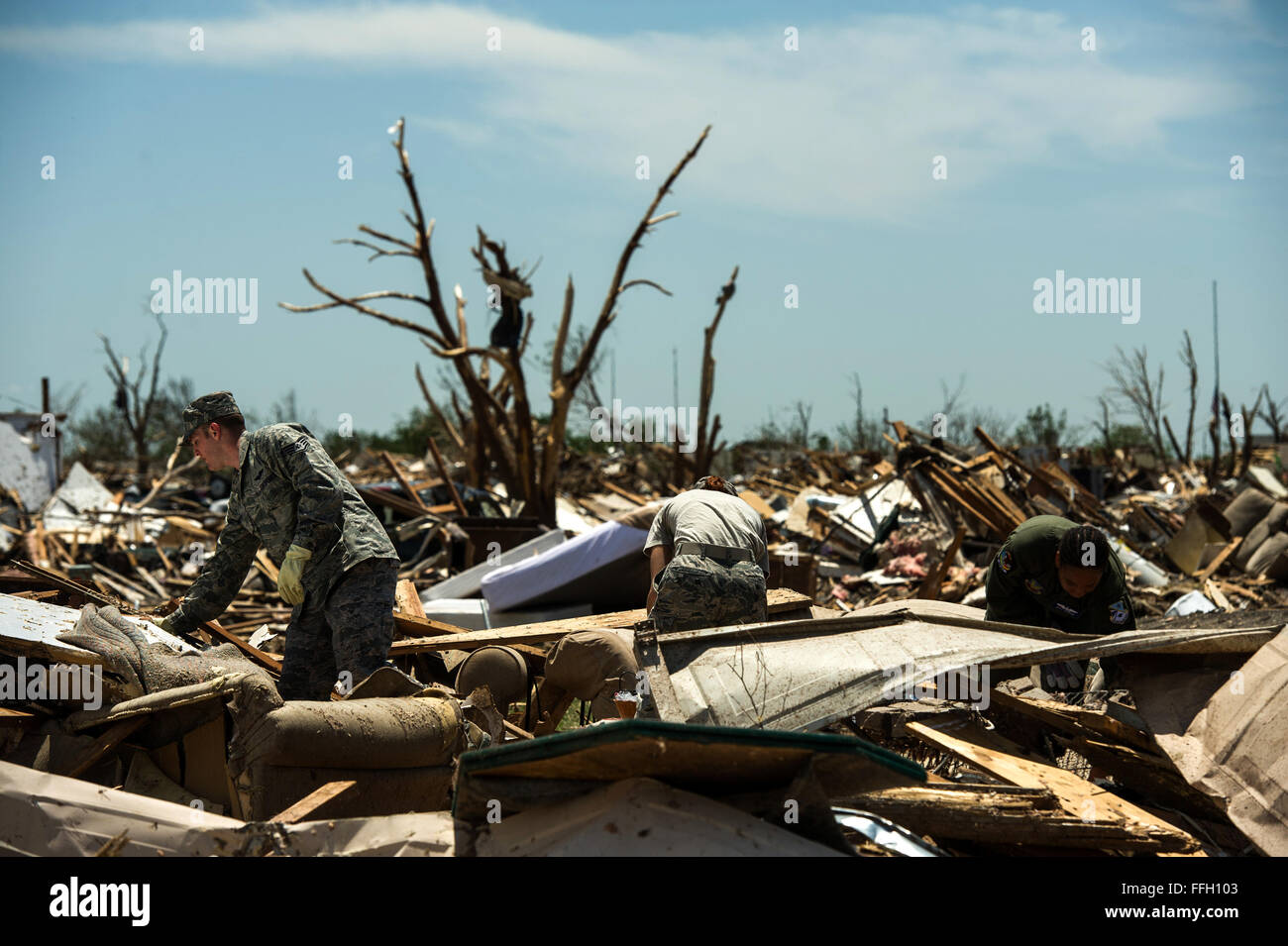 U.S. Air Force Airmen from the 966th Airborne Air Control Squadron help a resident  in Moore, Okla. search through the debris looking for salvageable items May 22, 2013. On Monday a EF-5 tornado, with winds reaching at least 200 mph, traveled for 20 miles, leaving a two-mile-wide path of destruction, leveling homes, crushing vehicles, and killing more than 20 people. More than 115 Oklahoma National Guard have been activated to assist in the rescue and relief efforts. Stock Photo