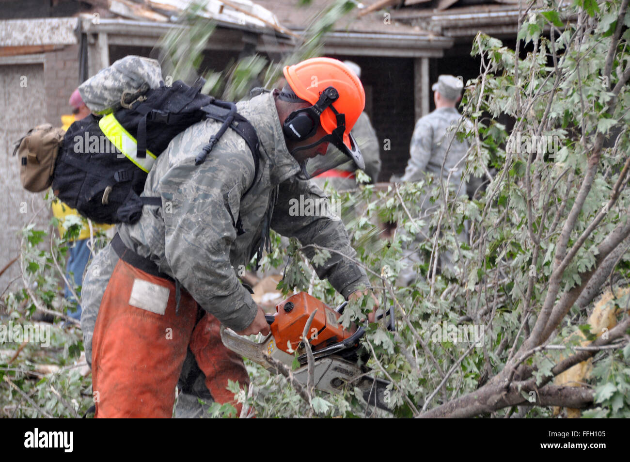 A military member cuts trees that were brought down on homes after a tornado hit the town of Moore, Okla. May 20, 2013. Stock Photo