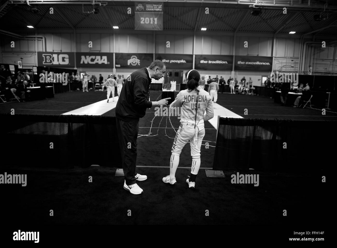 After consecutive losses during the 2014 NCAA Fencing Championships, Air Force Academy Fencing Head Coach Abdel Salem talks to Alyssa Hofilena to help correct some of her mistakes. Hofilena finished the championships ranked 11th out of 24 in the women's saber category. Stock Photo