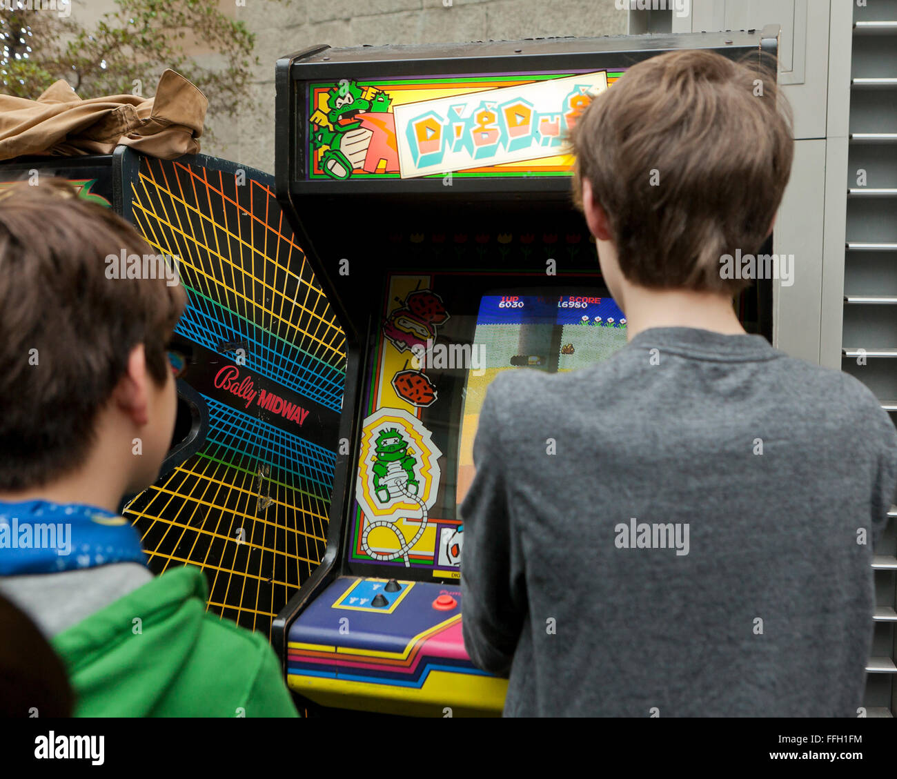 Young boys playing the classic Dig Dug video arcade game - USA Stock Photo