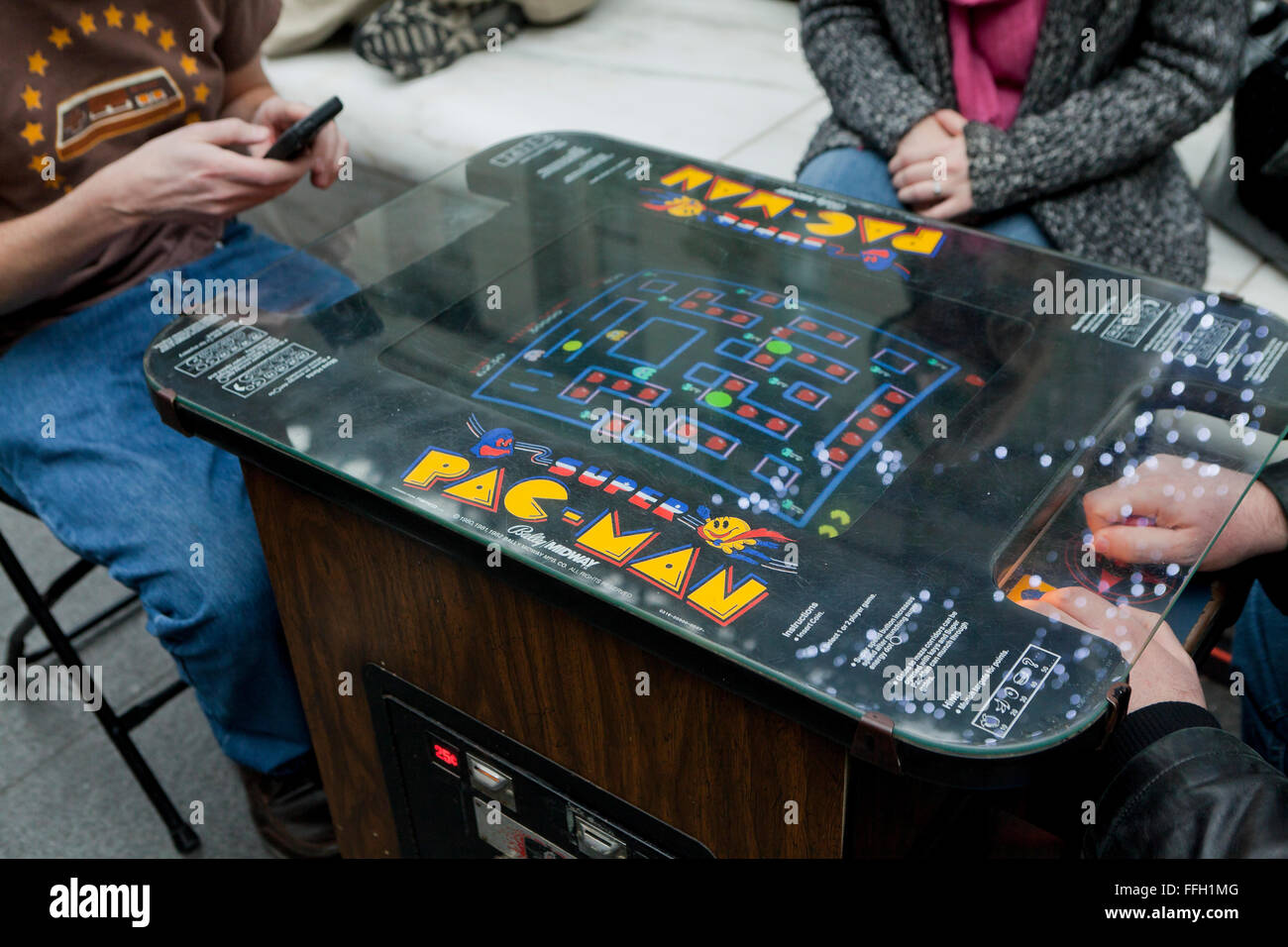 People playing a vintage Pac-Man video arcade game - USA Stock Photo