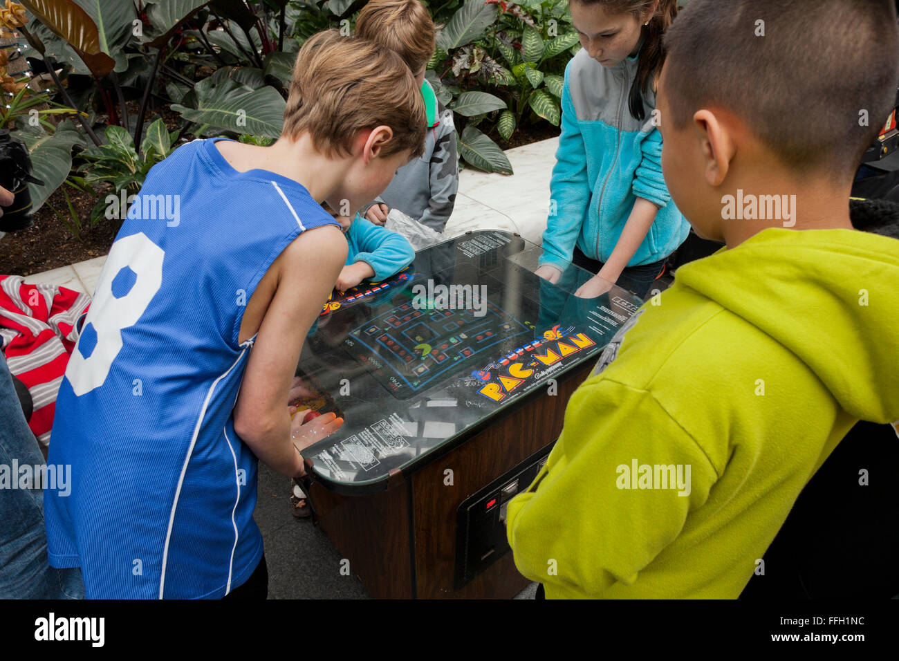 Young children playing the classic Pac-Man video arcade game - USA Stock Photo