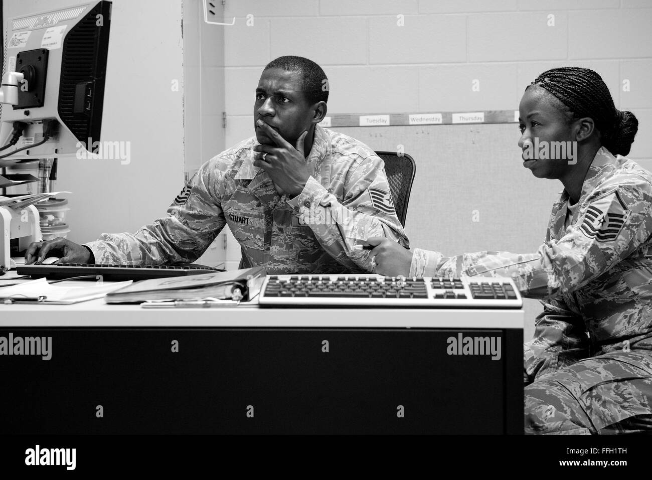 Military training instructors, Tech. Sgt. Chananyah Stuart, and Master Sgt. Tequilla Johnson, prepare graduation paperwork while their flight of trainees prepares the dorm for inspection. Stock Photo