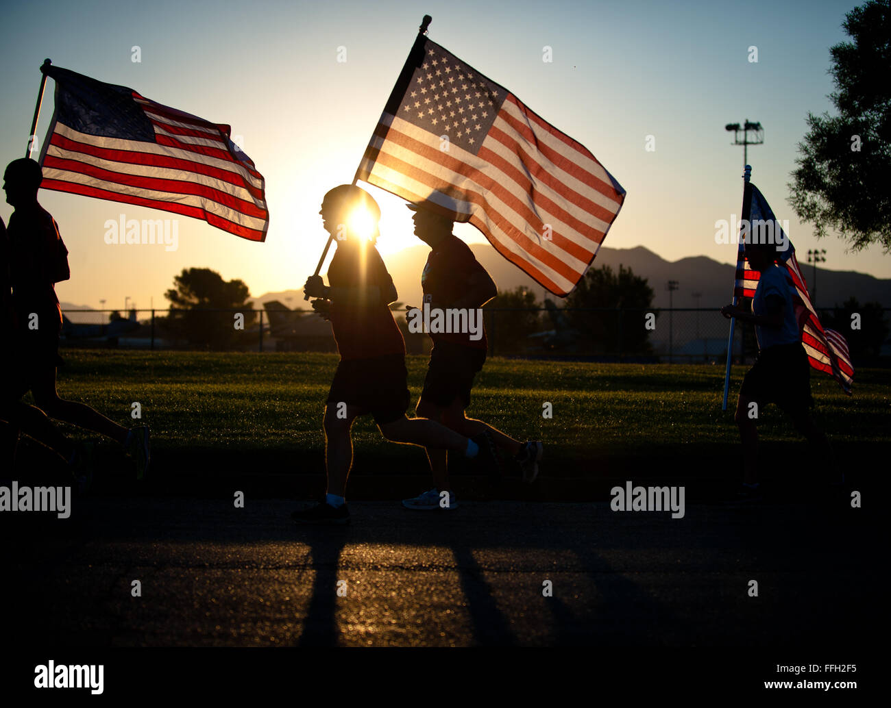 Members of Nellis Air Force Base run with the American flag Sept. 11, 2014, during the Old Glory Challenge at Nellis AFB, Nev. During the challenge, participants were charged with continuously running with the flag in 30-minute increments from 6:30 a.m. to 4:30 p.m. The goal of the event was to help participants remember the events of 9/11, honor those lost in defending freedom and tell the story of all who serve in defense of freedom. Stock Photo
