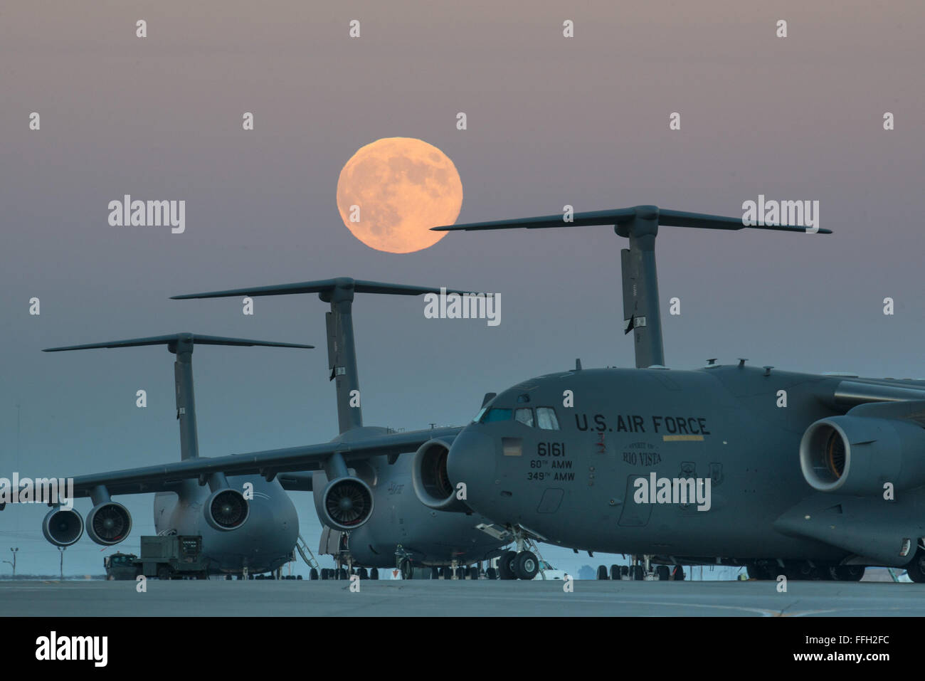 The ÔsupermoonÕ rises over the flightline at Travis Air force Base, Calif.  Supermoons are full moons that coincide with Ôlunar perigee,Õ when the moon's orbit brings it closest to Earth. Stock Photo