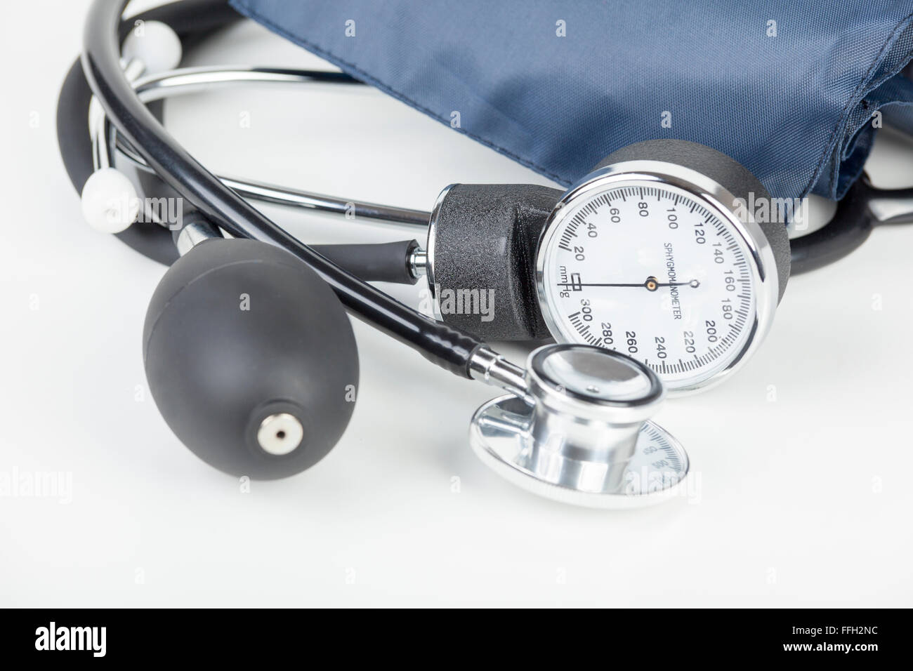 Close up of a sphygmomanometer and stethoscope laying on a white