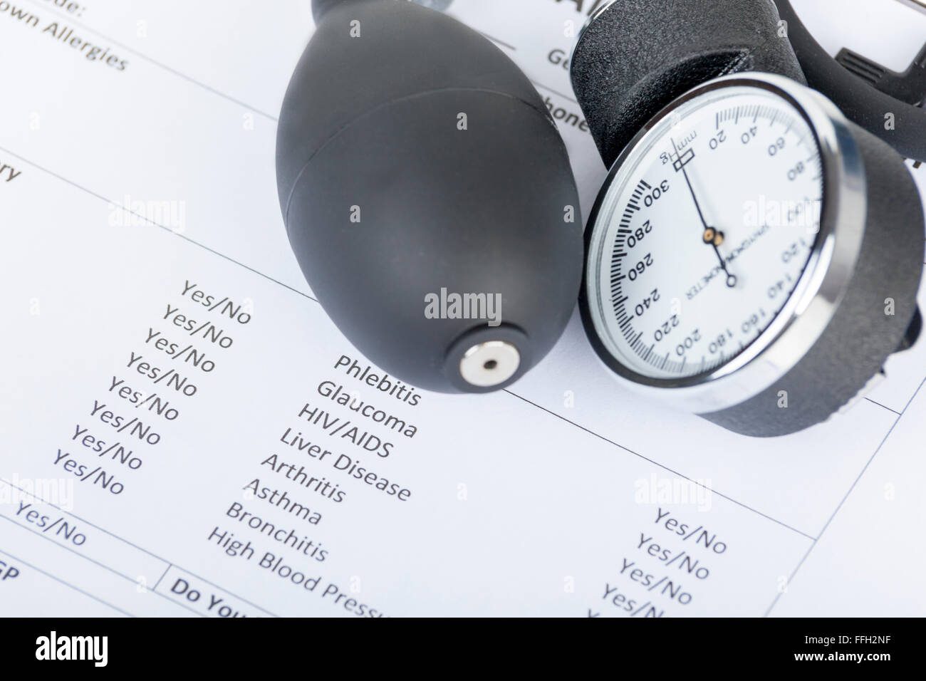 Part of a sphygmomanometer laying on a medical questionnaire form Stock