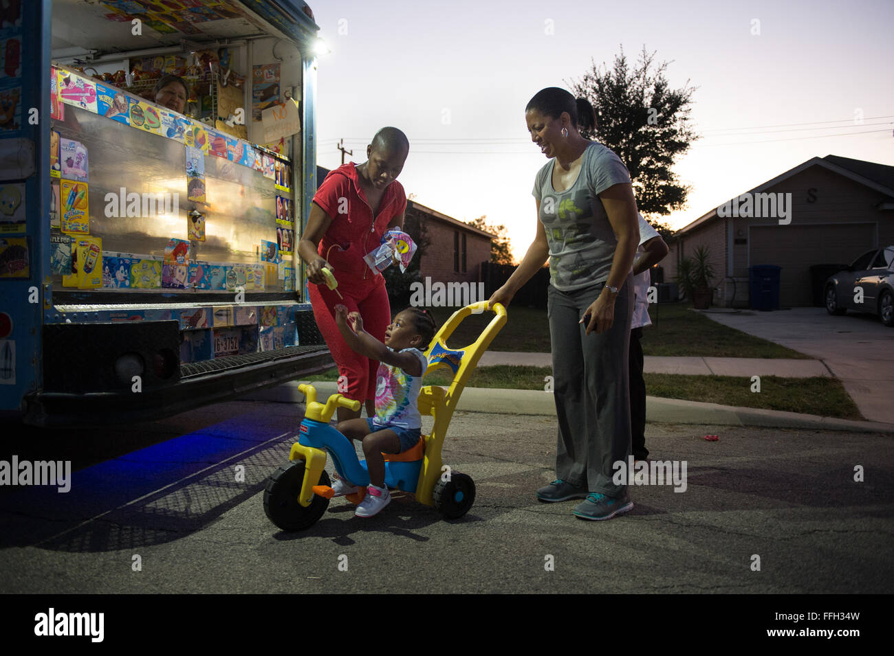 Somaya, 2, daughter of Staff Sgt. Chantel Thibeaux, Joint Base-Fort Sam Houston, Texas, dental assistant instructor, reaches up for Ice cream as her grandmother Carla guides her Big Wheel.  At two years old, Somaya is unaware of her mothers battle with cancer and tried to play with her every chance she can, but is limited to certain activities. About 15 family and friends gathered at her house to celebrate a successful surgery and provide love to Thibeaux during her quest to defeat cancer. Stock Photo