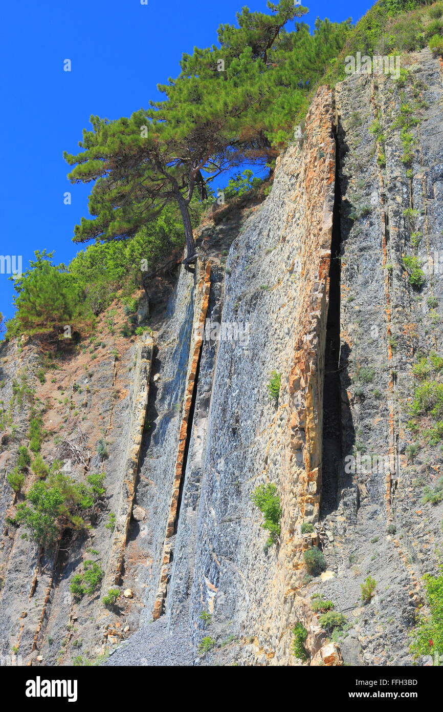 Steep slopes with sparse vegetation and visible layers of rock Stock Photo