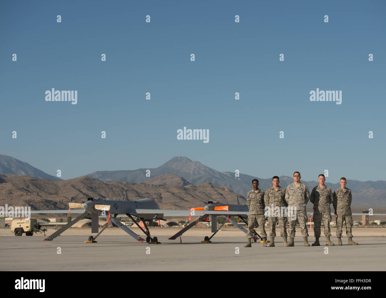 Remotely piloted aircraft maintainers assigned to the 432nd Aircraft Maintenance Squadron stand together after pushing two MQ-9 Reapers into parking spaces at Creech Air Force Base, Nevada. RPA maintainers manually park the aircraft in designated locations to prepare them for future missions. More than 100 personnel are involved in launching one RPA mission. Stock Photo