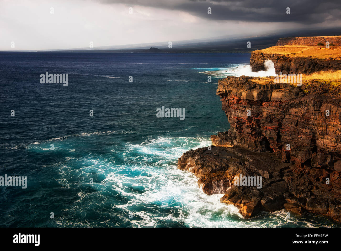Waves crash against the volcanic cliffs on the southern most point in the USA at South Point and the Big Island of Hawaii. Stock Photo