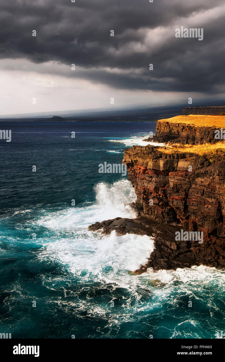 Waves crash against the volcanic cliffs on the southern most point in the USA at South Point and the Big Island of Hawaii. Stock Photo