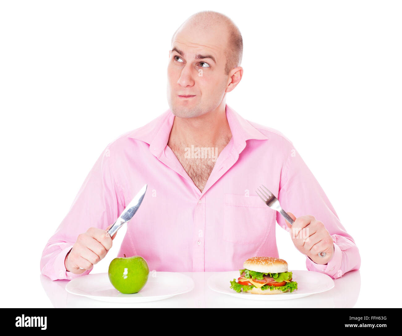 Caucasian man undecided if he is gonna go for the apple or for the hamburger, isolated on white background. Stock Photo