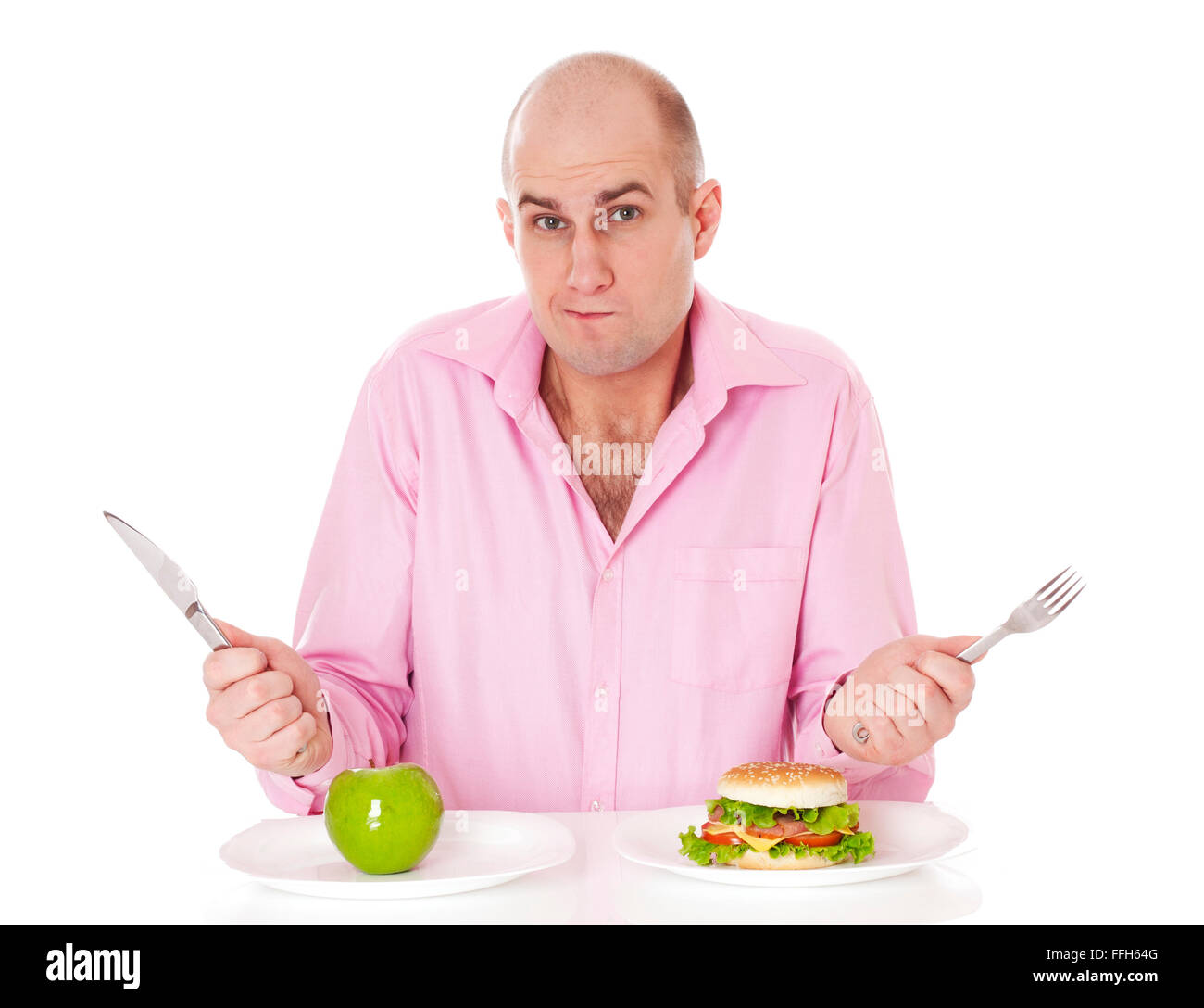Caucasian man undecided if he is gonna go for the apple or for the hamburger, isolated on white background. Stock Photo