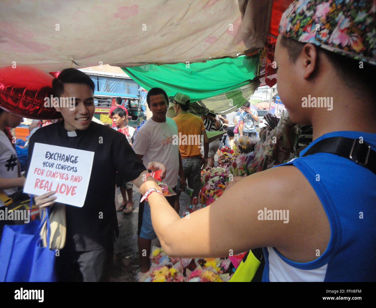 Manila, Philippines. 14th Feb, 2016. Members of a pro-life group give away candies in exchange for condoms at the Dangwa flower market in Manila, Philippines on Valentine's Day. Valentines Day is celebrated on February 14 every year. Credit:  Richard James M. Mendoza/Pacific Press/Alamy Live News Stock Photo