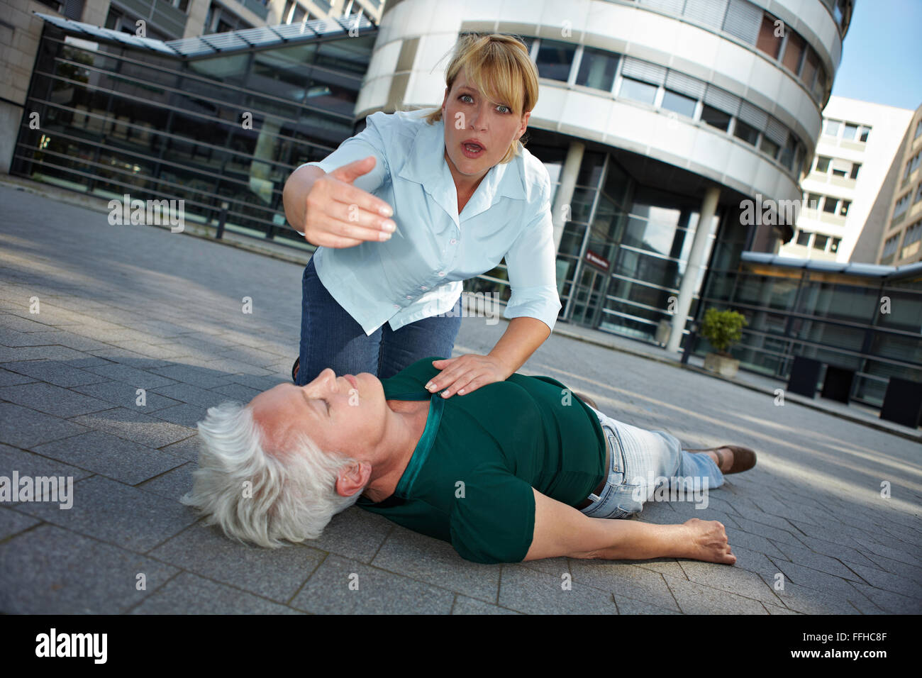 Passerby with unconscious senior woman asking for First Aid help Stock Photo