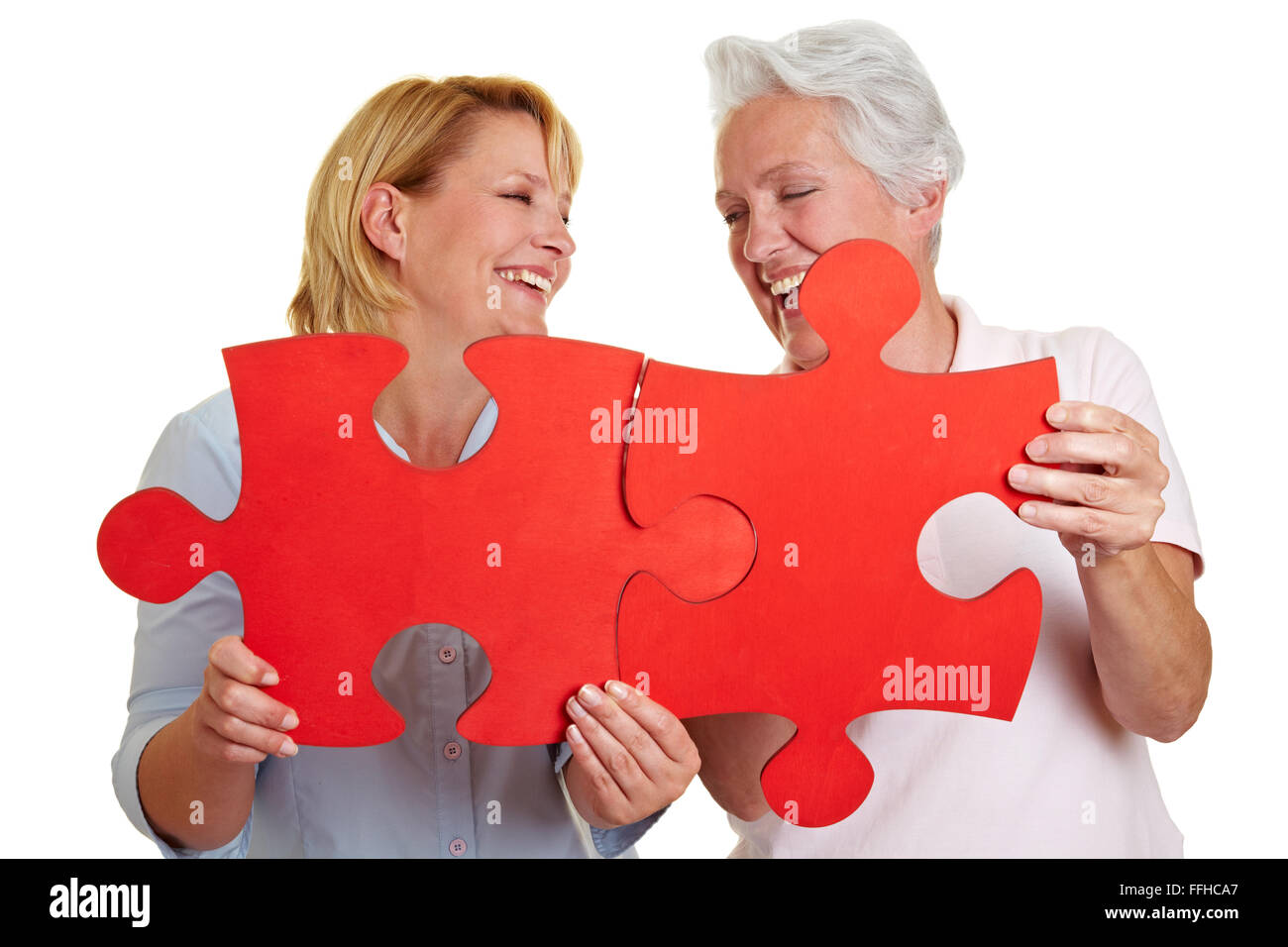Two happy senior women holding jigsaw puzzle pieces Stock Photo