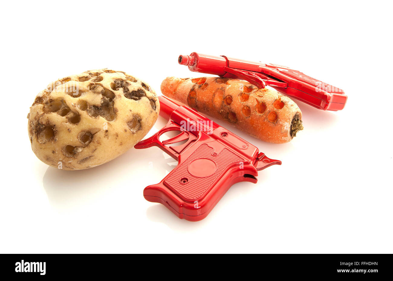Retro Christmas toys, two red Spud Guns with potato and carrot on white background Stock Photo