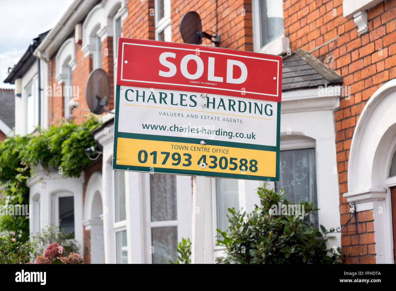 The marketing for sale sign boards of local estate agent Charles Harding outside homes on a street in Swindon Wiltshire UK Stock Photo