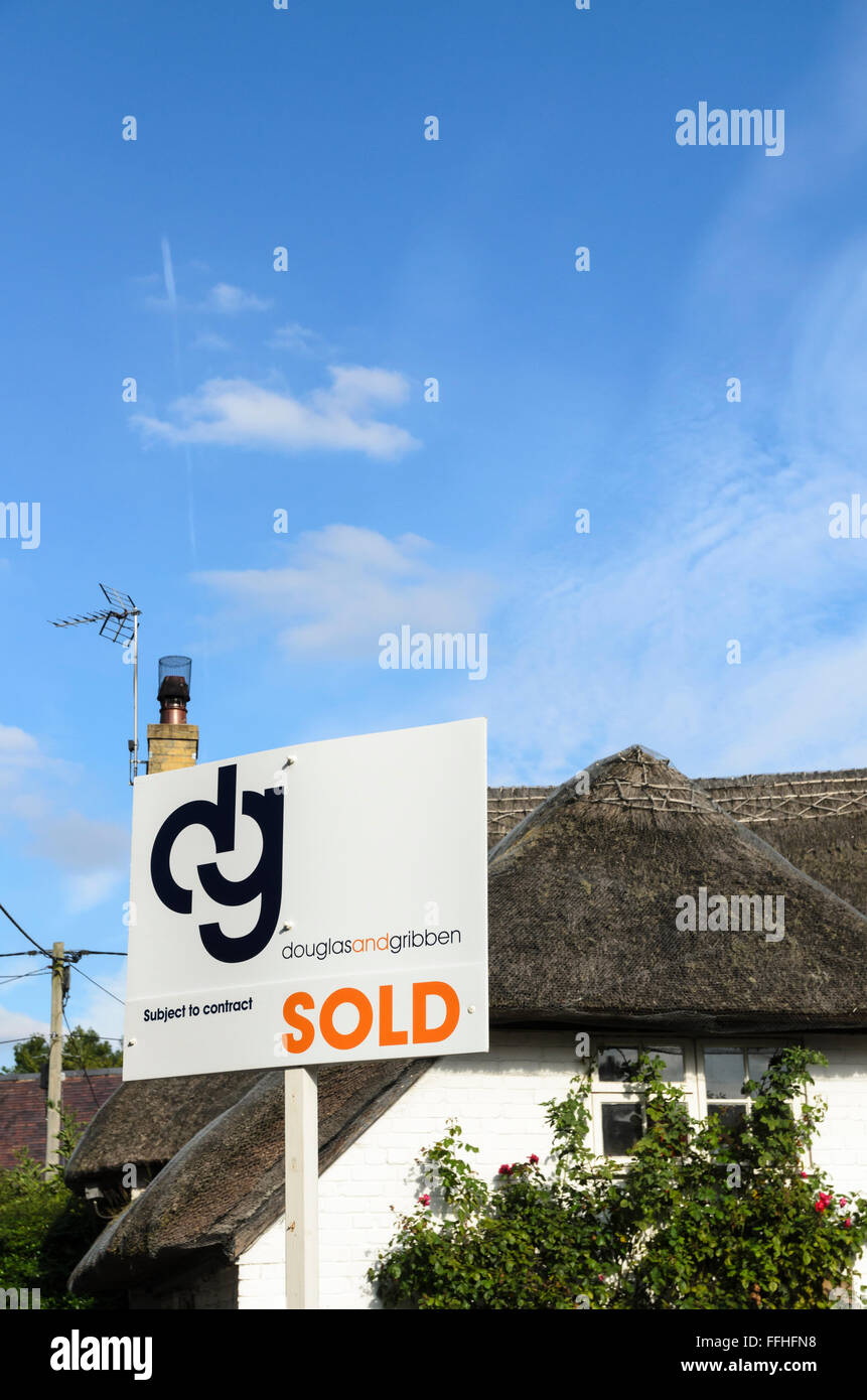 An estate agents sign outside a thatched cottage in Uffington, Oxfordshire, England, UK. Stock Photo