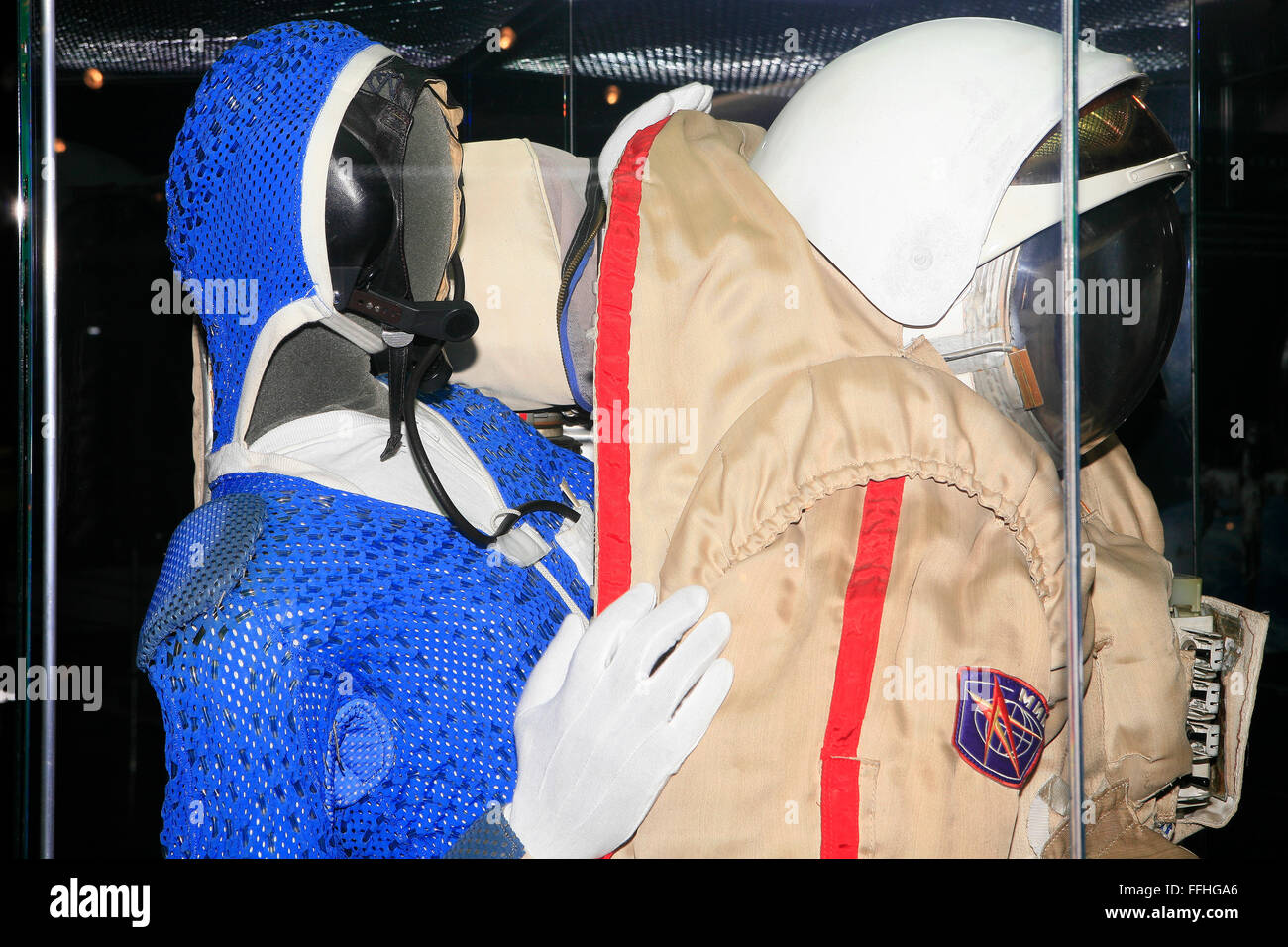 A Russian cosmonaut in a blue flight suit entering his space suit at