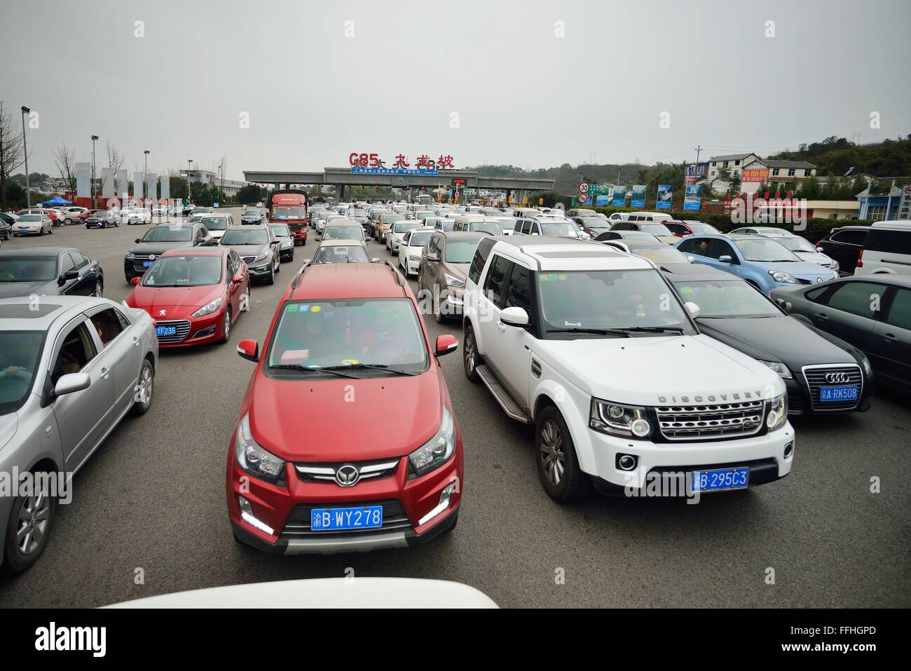 Chongqing, China. 13th Feb, 2016. Vehicles queue to pass the Jiulongpo Toll Station on the Chongqing-Kunming Highway in Chongqing, southwest China, Feb. 13, 2016. Chinese passengers made a record number of trips during the Spring Festival holiday, according to the Ministry of Transport (MOT) on Sunday. Passenger trips reached 400 million from Feb. 7 to 13, up 6.7 percent from last year, MOT data showed. Over 47 million trips were made by rail, more than 333 million on road and about 8.5 million by air. Road trips were up by 7 percent. Credit:  Chen Xingyu/Xinhua/Alamy Live News Stock Photo
