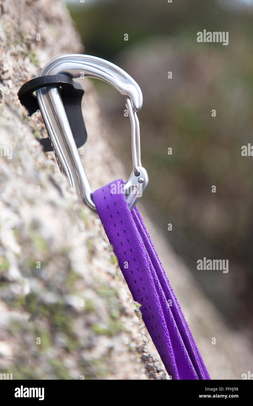 Rock climbing carabiner on rock with purple rope. Stock Photo