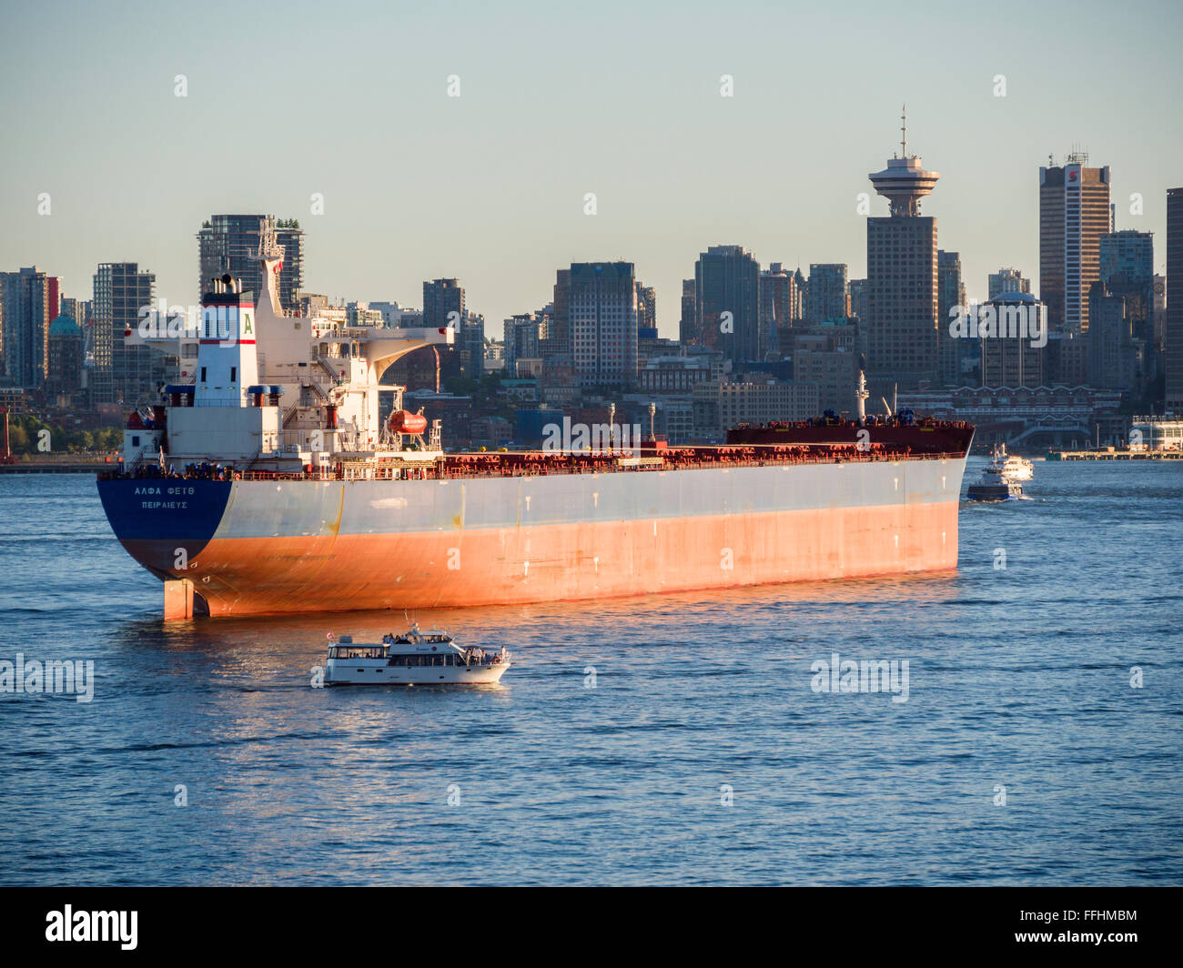 Bulk carrier 'Alpha Faith' (2008) awaits loading or unloading in Vancouver Harbour in front of Vancouver skyline. Stock Photo
