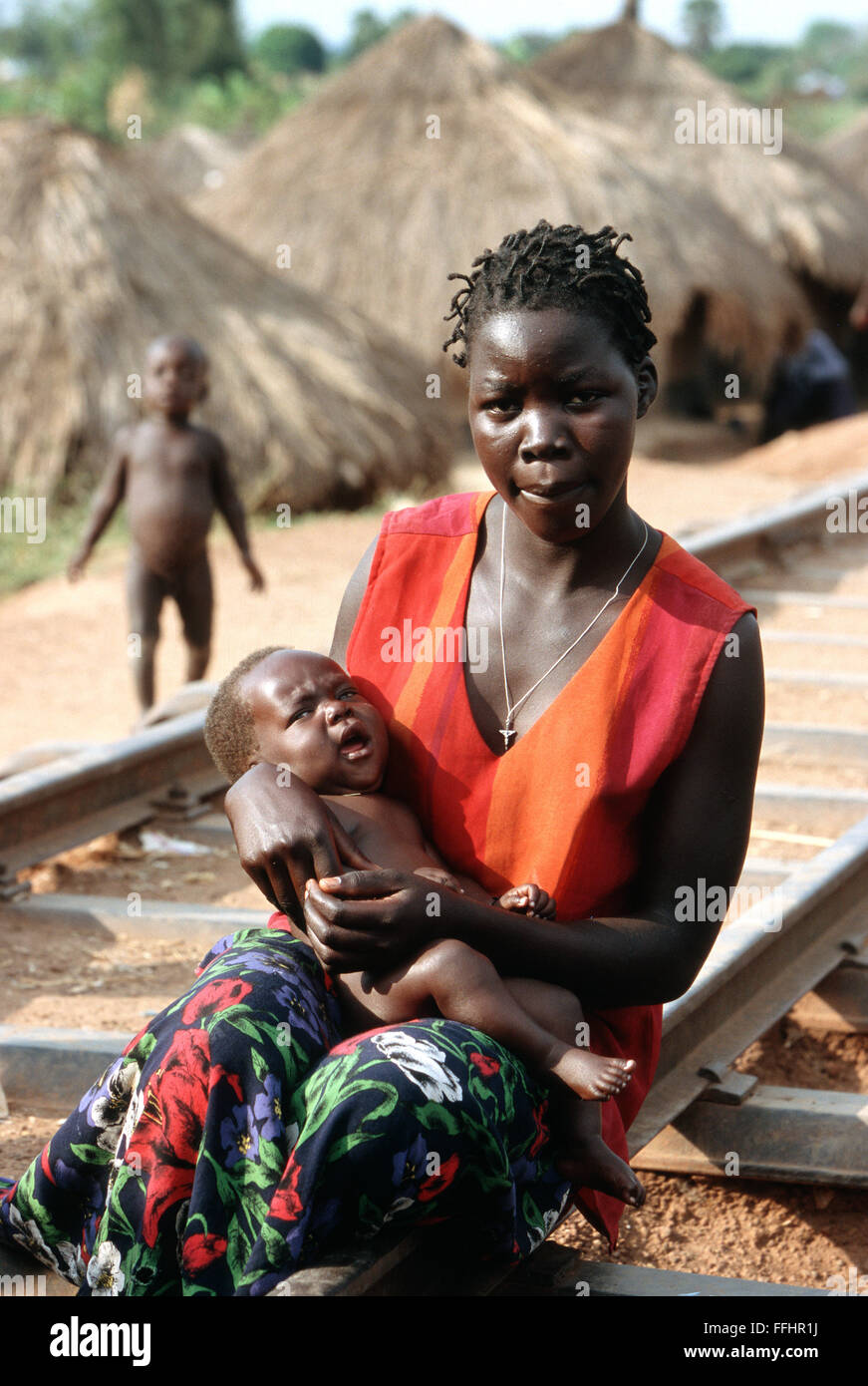 Mother with her baby sitting on railway tracks in a Refugee Camp in Lira, Northern Uganda. These refugees fleeing the LRA rebels attacking the northern Uganda. Stock Photo
