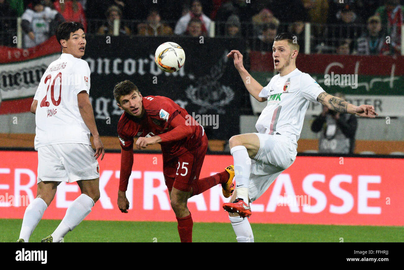 Augsburg, Germany. 14th Feb, 2016. Augsburg's Jeong- Ho Hong (l) and Jeffrey Gouweleeuw (r) compete for the ball with Thomas Mueller of Munich during the German Bundesliga football match between FC Augsburg and Bayern Munich at the WWK-Arena in Augsburg, Germany, 14 February 2016. PHOTO: STEFAN PUCHNER/DPA (EMBARGO CONDITIONS - ATTENTION - Due to the accreditation guidelines, the DFL only permits the publication and utilisation of up to 15 pictures per match on the internet and in online media during the match) Credit:  dpa/Alamy Live News Stock Photo
